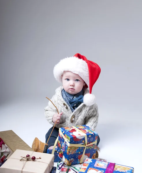 Bebê alegre com caixas de presente usando chapéu de santa — Fotografia de Stock