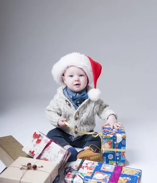 Vidám baba ajándék dobozok viselt santa kalap — Stock Fotó