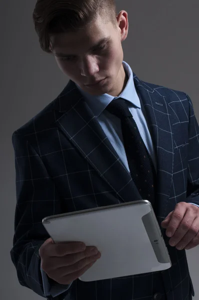 Hombre galante guapo con tableta sobre fondo gris . — Foto de Stock