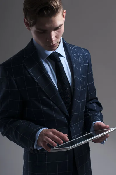 Hombre galante guapo con tableta sobre fondo gris . — Foto de Stock