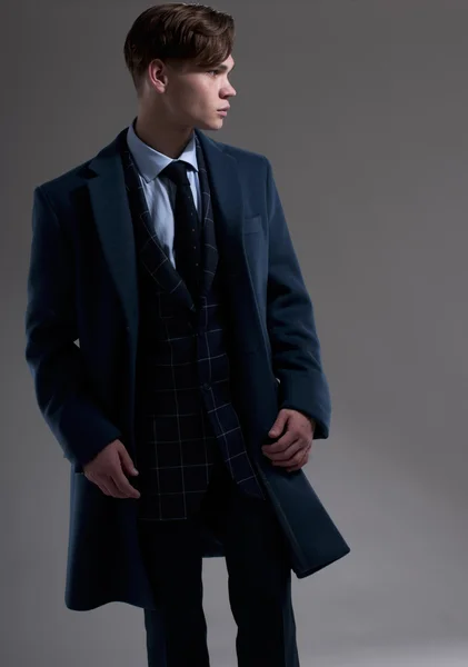 Jeune homme séduisant porte costume avec manteau sur fond gris — Photo