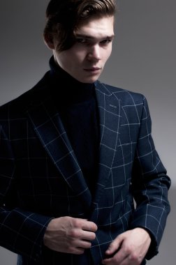 ciddi bir adam gri arka plan üzerinde bir palto giyiyor.