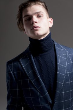 ciddi bir adam gri arka plan üzerinde bir palto giyiyor.