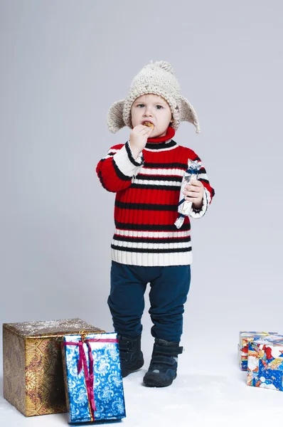 Criança em roupas de inverno entre um monte de caixas de presente — Fotografia de Stock