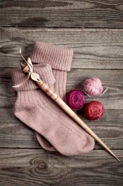 Retro wooden spindle and purple knitted socks with  a ball of ya — Stock Photo, Image