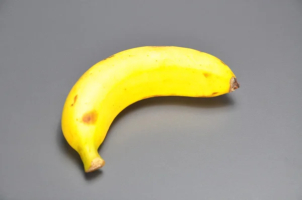 Banán na šedém pozadí — Stock fotografie