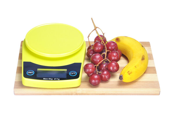 crimson grape, banana and electronic kitchen scale on bamboo cho