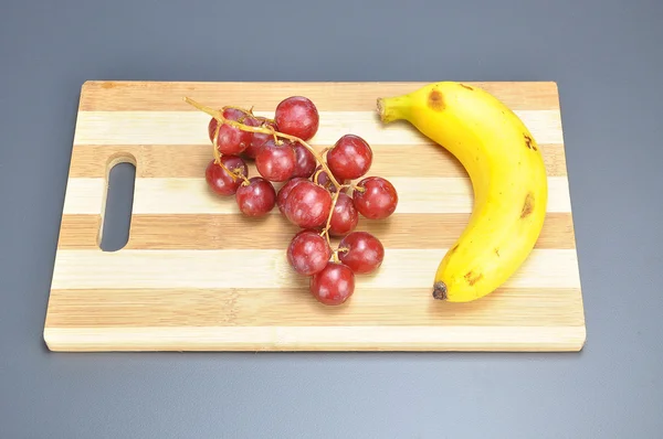 Смачна пучка червоного безсіяного малинового винограду та банана на бамбуку — стокове фото