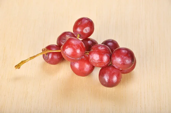 Delicioso cacho vermelho sem sementes de uva carmesim na prancha de madeira — Fotografia de Stock