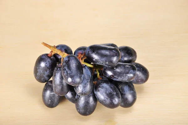 Deliciosa e fresca uva preta sem sementes na tábua de madeira — Fotografia de Stock