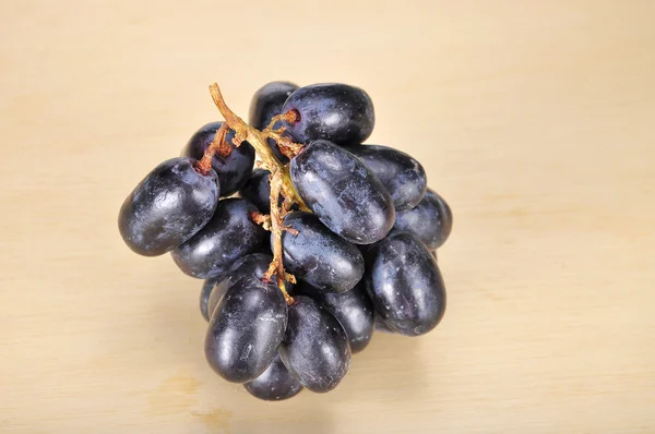 Deliciosa e fresca uva preta sem sementes na tábua de madeira — Fotografia de Stock