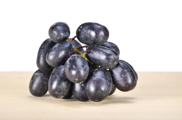 Deliciosa e fresca uva preta sem sementes na tábua de madeira — Fotografia de Stock