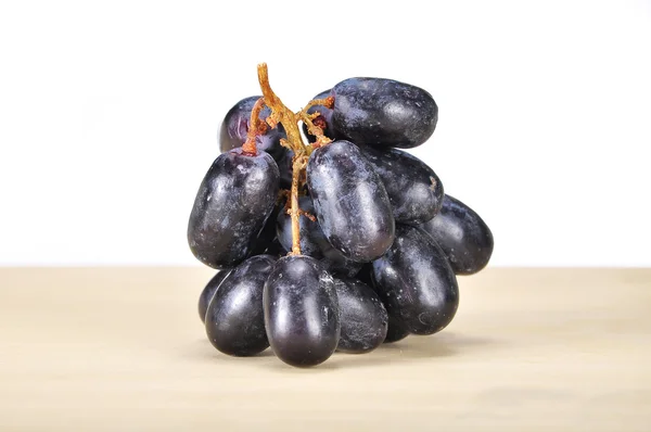 Deliciosa e fresca uva preta sem sementes na tábua de madeira — Fotografia de Stock