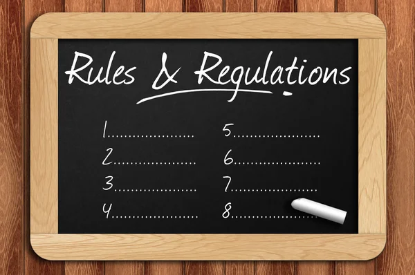 Chalkboard on the wooden table written rules & regulations list — Stock Photo, Image