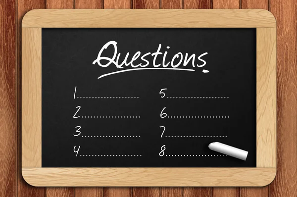質問リストを書かれた木製のテーブルの上の黒板 — ストック写真