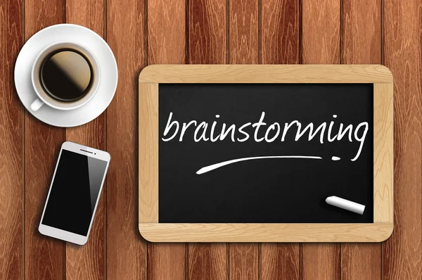 Café, telefone e quadro com palavra brainstorming — Fotografia de Stock