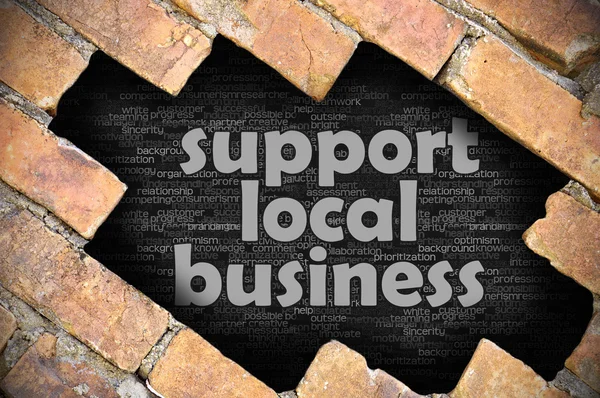 Τρύπα στον τοίχο τούβλου με λέξη υποστήριξη τοπικών επιχειρήσεων — Φωτογραφία Αρχείου