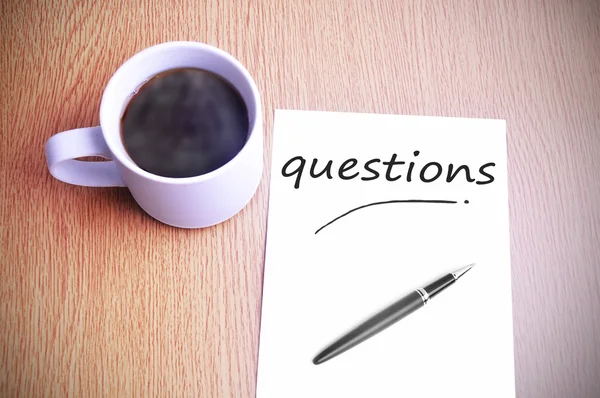 Káva na stůl s poznámkou psaní otázky — Stock fotografie
