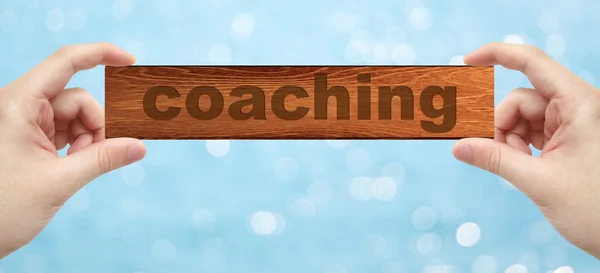 Handen met een hout graveren met woord coaching — Stockfoto