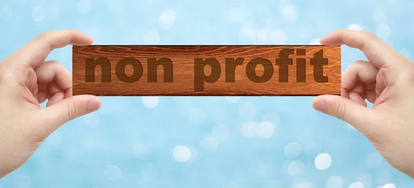Handen met een hout graveren met woord non-profit — Stockfoto