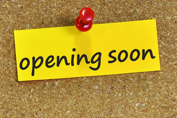 opening soon word on yellow notepaper with cork background