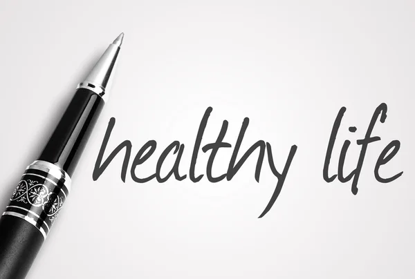 Pen schrijft gezond leven op witte blanco papier — Stockfoto
