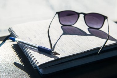 Kalem, gözlük, arabanın ön paneline not defteri. Yoldan gelen notlar.