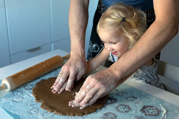 Genç baba ve küçük tatlı kızı mutlu bir şekilde birlikte Noel kurabiyesi yapıyorlar. Mutfak yeni yıl için dekore edildi..