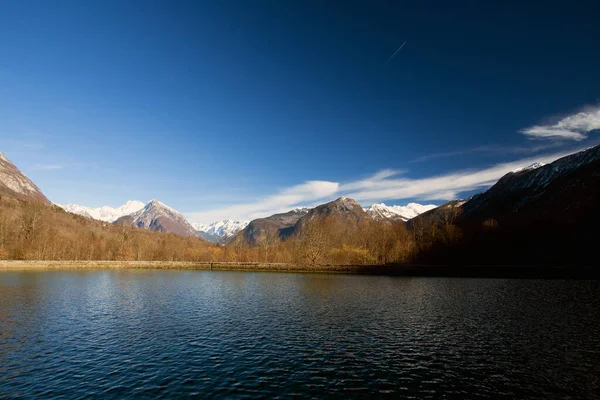 Spring scenery with lake, mountain peaks, forest and blue sky. Afternoon sunset. Slovenia. Copy space