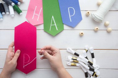 Evde işlemeli harflerle keçeli bayrak nasıl yapılır? Adım adım talimatlar. Eller DIY projesi yapıyor. Altıncı adım: İşlemeli harfler ana hatlı dikiş ya da en sevdiğin dikişle işlenmiş.