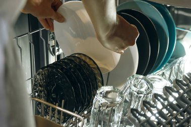 Kadın elleri bulaşık makinesinden temiz tabak çıkarıyor. Oda servisi ve ev hayatı kavramı.