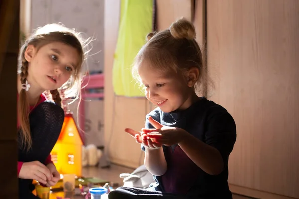 Dos chicas jugando juntas bajo la luz del sol de la mañana sentadas en el suelo. Concepto infantil despreocupado. — Foto de Stock