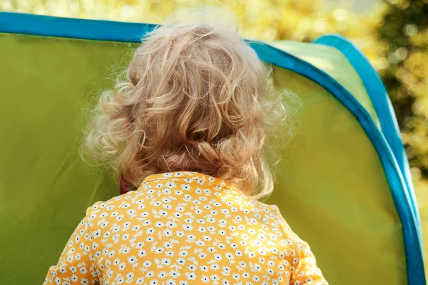 Petite fille aux cheveux bouclés blonds regardant dans la tente. — Photo