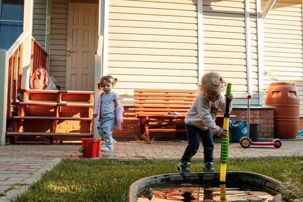Enfants jouant dans le jardin avec pompe à eau près d'un petit étang. — Photo
