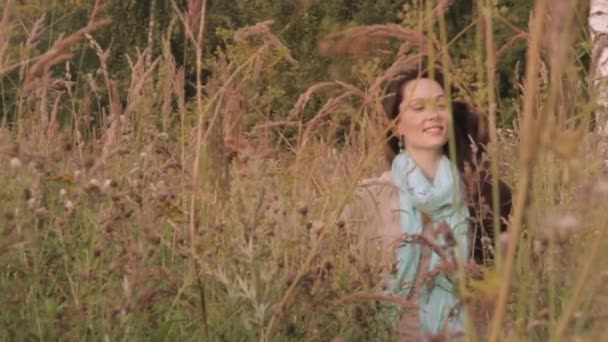 Onnellinen ja nautinnollinen nuori nainen kävelee kentän ruohon läpi. — kuvapankkivideo