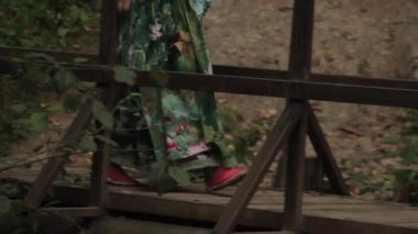 Genç bir kadın yavaşça tahta köprüden geçiyor..