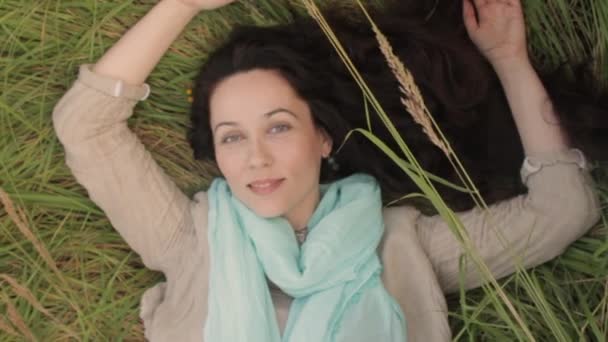 Jeune femme relaxant couché dans l'herbe des champs. — Video