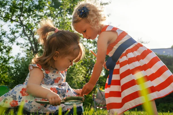 Children playing in the garden with magnifier.