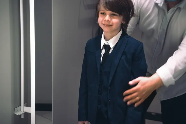 Sonriente niño y su padre tratando de uniforme escolar para el futuro escolar. — Foto de Stock