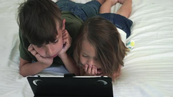 Děti sledující tablet při ležení na posteli. — Stock video