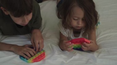 Kız ve erkek yatakta uzanırken oyuncak bebek oynuyorlar..
