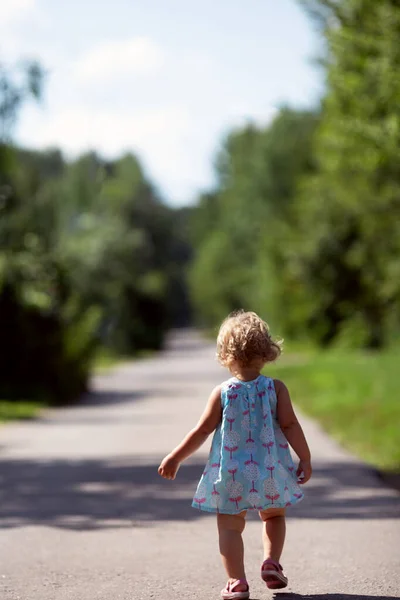 Dziewczynka spacerująca ulicą. Widok z tyłu. Beztroskie dzieciństwo Obraz Stockowy
