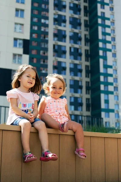 Deux petites filles assises à l'extérieur paysage urbain. Format vertical, sœurs — Photo