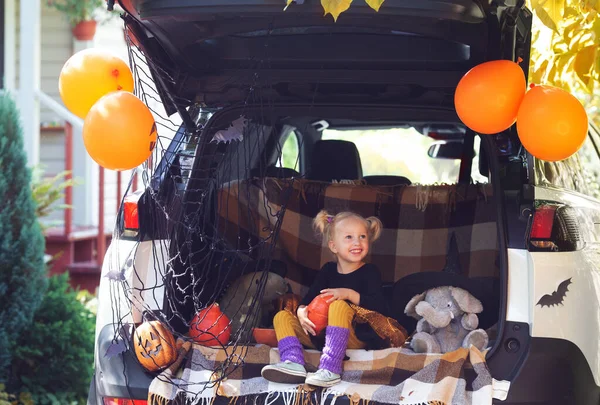 Little girl celebrating Halloween car trunk. Stay home. Autumn holidays.