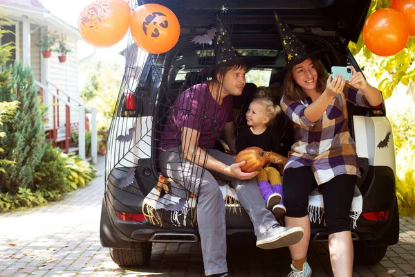 Family celebrating Halloween car trunk. Having fun together. Autumn