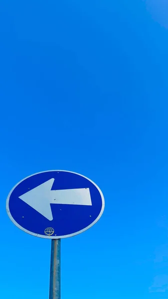 Açık bir gökyüzünün arka planında mavi yol işareti
