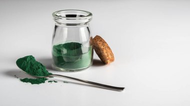 Camdaki klorella yosun tozu ve beyaz arka plandaki kaşıkta.