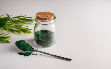 Camdaki klorella yosun tozu ve beyaz arka plandaki kaşıkta.. 