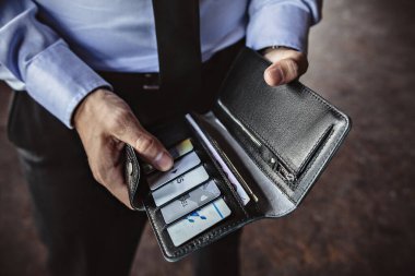 İş adamı deri cüzdanından bir kredi kartı çıkardı.