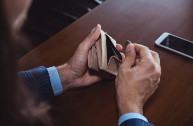 Kafedeki bir masada oturan bir adam cüzdanından para alıyor.